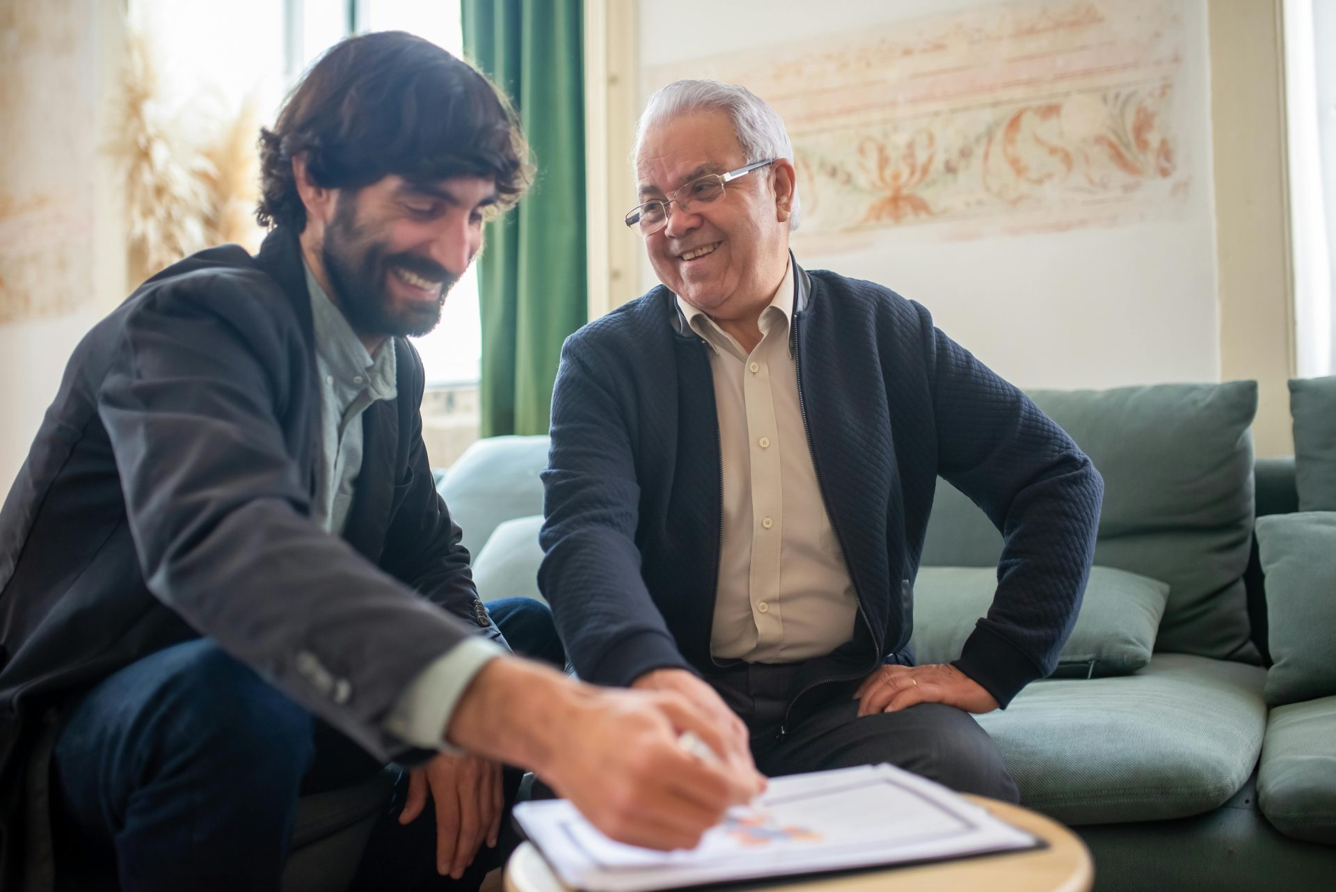 An advisor and elderly client discussing documents during a consulting session indoors.